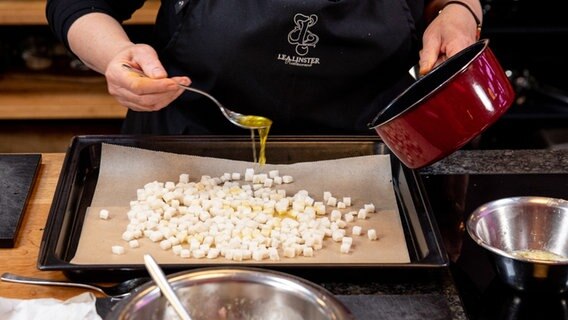 Weißbrotwürfel für einen Salat werden mit geschmolzener Butter übergossen . © NDR Foto: Claudia Timmann