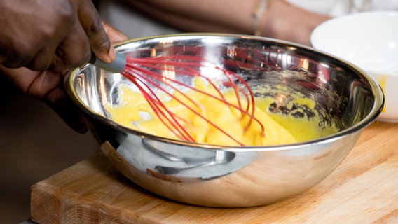 Ein Koch verrührt in einem Topf  Eigelb mit Zucker. © NDR Foto: Claudia Timmann