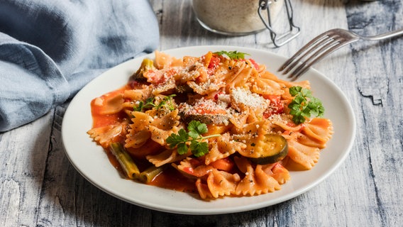 Ein Teller mit Farfalle und Gemüse sowie Parmesan. © picture alliance / Westend61 Foto: Eva Gruendemann