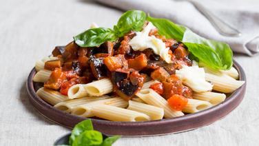 A plate of penne with eggplant and mozzarella is on a table.  © NDR Photo: Claudia Timmann