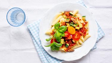 Penne mit Tomaten-Bolognese und ein Glas Wasser stehen auf dem Tisch. © NDR Foto: Claudia Timmann