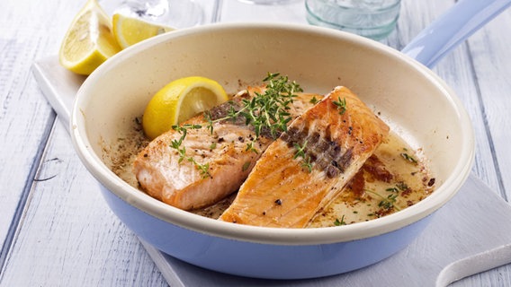 Two salmon fillets with a piece of lemon in an enamel pan.  © fotolia.com Photo: HLPhoto