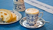 Eine Tasse Kaffeepunsch steht neben einem Stück Kuchen auf dem Tisch. © picture-alliance / DUMONT Bildarchiv 