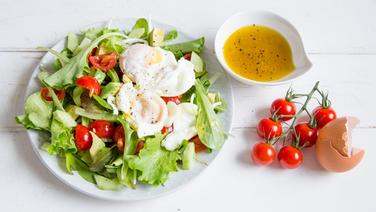 Ein Teller mit Salat und porchierten Eiern steht auf einem Tisch. © NDR Foto: Claudia Timmann