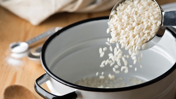 Reis rieselt in einen Topf. © cobraphoto/fotolia Foto: cobraphoto