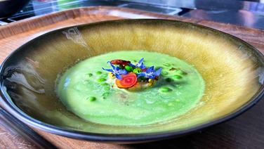 Ein Gurken-Stachelbeersüppchen mit gegrilltem Gartengemüse ist auf einem rustikalen Teller angerichtet.  ©NDR 