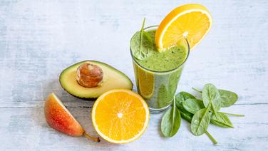 Ein Algen-Smoothie, daneben eine aufgeschnittene Orange sowie Birne und Avocado. © NDR Foto: Claudia Timmann