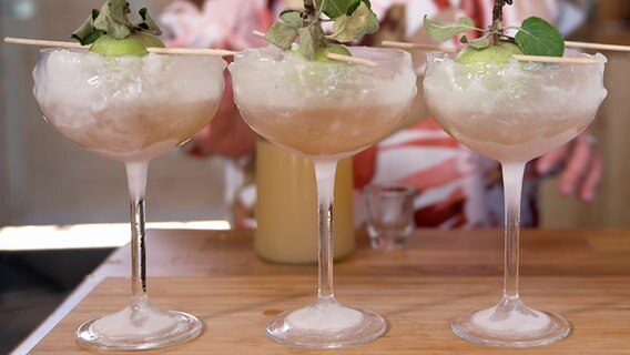 Drei Cocktail-Gläser mit einem Kräuter-Aperitif. © NDR 