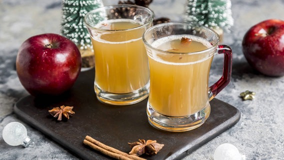 Zwei Gläser mit Apfelpunsch stehen auf einem Tisch mit weihnachtlicher Dekoration. © imago/Westend61 Foto: Sandra Roesch