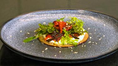Buchweizen-Blini mit gebeizter Paprika, Meerrettichcreme und Wildkräutersalat auf einem Teller serviert. © NDR 