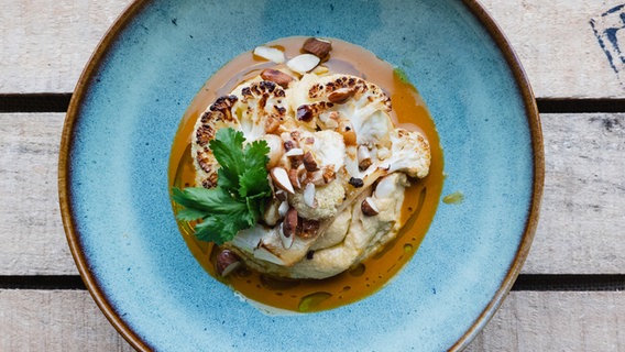 Blumenkohl mit Curry-Dip und Kichererbsen-Mandelcreme auf einem Teller serviert. © NDR Foto: Tarik Rose