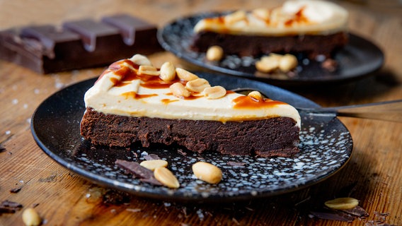 Ein Stück Brownie mit mit Erdnusscreme und Karamell auf einem Teller serviert. © NDR Foto: Claudia Timmann