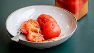 Eingekochte Tomaten auf einem hellen Teller, daneben ein Weckglas © NDR Foto: Claudia Timmann