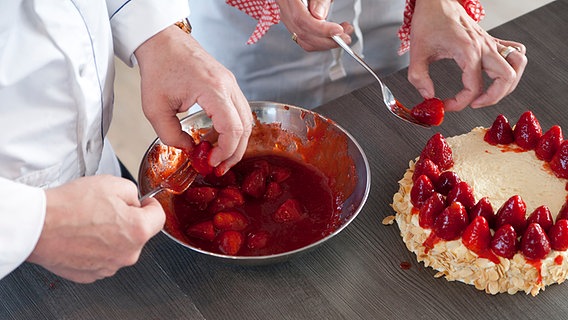 Ein Bäcker belegt einen Tortenboden mit Erdbeeren © NDR Foto: Claudia Timmann