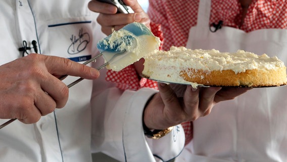 Ein Bäcker verteilt Buttercreme auf einem Biskuitboden. © NDR Foto: Claudia Timmann