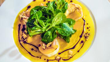 Ein Teller mit sautierten Garnelen , Feldsalat und eingelegtem Kürbis © NDR 