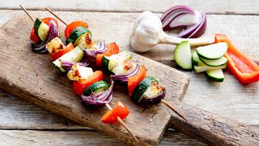 Auf einem Holzbrett liegen zwei Halloumi-Grillspieße.  Foto: Claudia Timmann