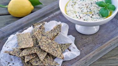 Cereal crackers on parchment and white bowl with herb bark © NDR Photo: Florian Kruck