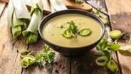 Eine Suppe mit Lauch, daneben und Im Hintergrund geschnittener Lauch. © Colourbox Foto: -