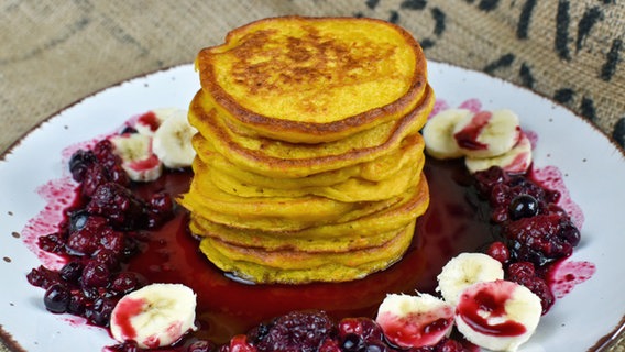 Vegane Kürbis-Pancakes mit Beeren und Banane auf einem Teller serviert. © veagnandlife.blog 
