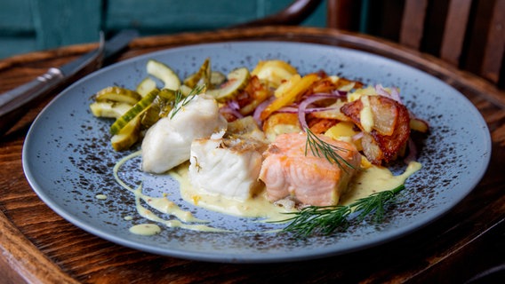 Pannfisch mit warmem Gurkensalat auf einem Teller serviert. © NDR Foto: Claudia Timmann