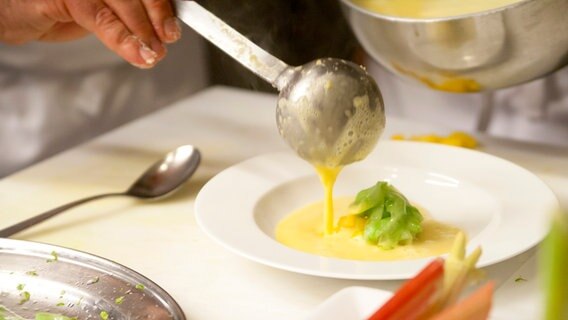 Paprika-Rhabarber-Suppe wird auf einen Teller gefüllt. © NDR Foto: Claudia Timmann