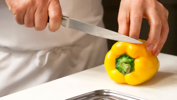 Eine gelbe Paprikaschote und ein Messer auf einem Küchenbrett. © NDR Foto: Claudia Timmann