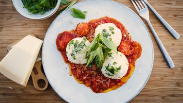 Quark dumplings served on a plate with tomato stew.  © NDR Photo: Tarik Rose
