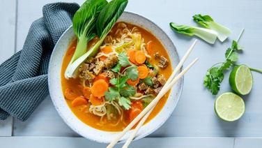 Eine Schale mit Curry-Ramen-Suppe, am Schalenrand ein Blatt Pak Choi sowie ein paar Stäbchen. © NDR Foto: Claudia Timmann