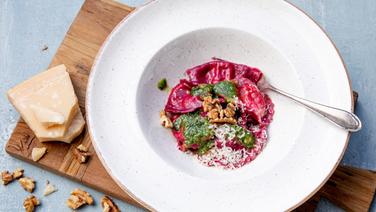 Rote-Bete-Nudeltaschen mit Ziegenfrischkäse-Füllung und Walnuss-Kräuterpesto auf einem Teller serviert © NDR Foto: Claudia Timmann