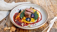 Saddle of venison with pumpkin risoni and blackberries served on a plate.  © NDR Photo: Claudia Timmann