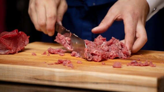 Ein Koch schneidet Rindfleisch klein für ein Tatar. © NDR Foto: Claudia Timmann