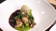 Rote-Bete-Käse-Praline auf Pilz-Spinat-Salat und Pesto angerichtet. © NDR 
