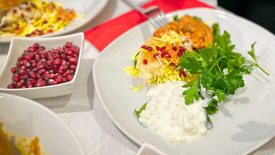 Safranhähnchen mit Basmatireis und karamellisierten Berberitzen auf einem Teller serviert © NDR Foto: Dave Hänsel
