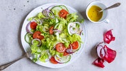 Ein bunter Salat auf einem Teller, daneben ein Schälchen mit Dressing. © NDR Foto: Claudia Timmann