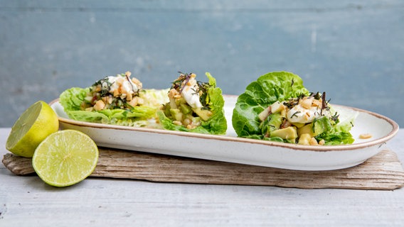 Avocado-Pfirsich-Salat in Salatblättern auf einer Platte serviert. © NDR Foto: Claudia Timmann