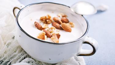 Eine Schale Skyr, darauf verteilt Mandeln und gehackte Nüsse. © Colourbox 
