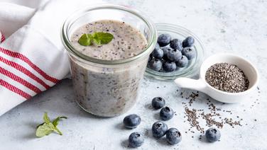 Ein Becher mit Flohsamen-Blaubeer-Smoothie, daneben einzelne Beeren. © NDR Foto: Claudia Timmann