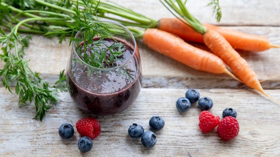 Ein Smoothie in einem Glas, daneben verschiedene Beeren. © Claudia Timmann 