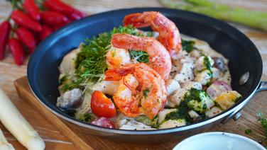 A pan with an asparagus and vegetable fricassee topped with prawns.  © NDR Photo: Florian Kruck