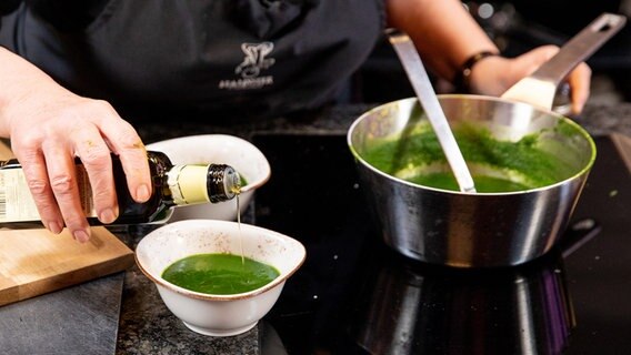 Eine Schale mit grüner Suppe wird mit etwas Olivenöl verfeinert. © NDR Foto: Claudia Timmann