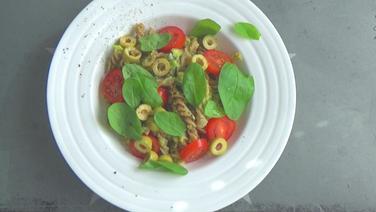 Legume pasta with avocado cream, garnished with basil leaves  