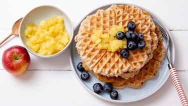 Buchweizen-Waffeln auf einem Teller, daneben und darauf Apfelmus und einige Blaubeeren. © NDR Foto: Claudia Timmann