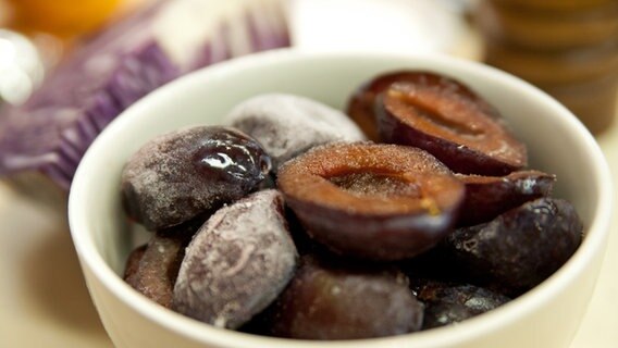 Gefrorene Zwetschgen liegen in einer Schüssel, dahinter ist ein Stück Rotkohl zu sehen. © NDR Foto: Claudia Timmann