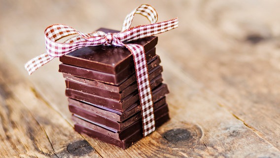 Ein kleiner Turm aus Schokoladen-Stücken mit Geschenkband. © fotolia Foto: Justinb