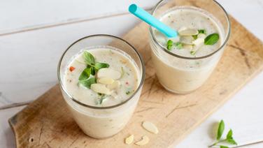 Zwei Gläser Kräuter-Smoothie mit Mandelmus stehen auf einem Holzbrett. © NDR Foto: Claudia Timmann