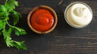 Tomatensoße und Mayonnaise in kleinen Schalen auf einem Holzbrett. © Colourbox Foto: Oksana Bratanova