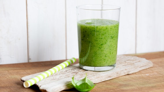 Spinat-Ananas-Smoothie in einem Glas auf einem Brett. Daneben liegt ein Strohhalm. © NDR Foto: Claudia Timmann