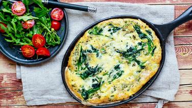 A plate of rocket salad and a pan of spinach omelette are on the table.  © NDR Photo: Claudia Timmann