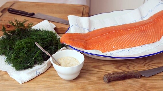 Dill, ein Zucker-Salzgemisch in einer Tasse und eine Lachsseite auf einem Küchentisch. © NDR Foto: Claudia Timmann